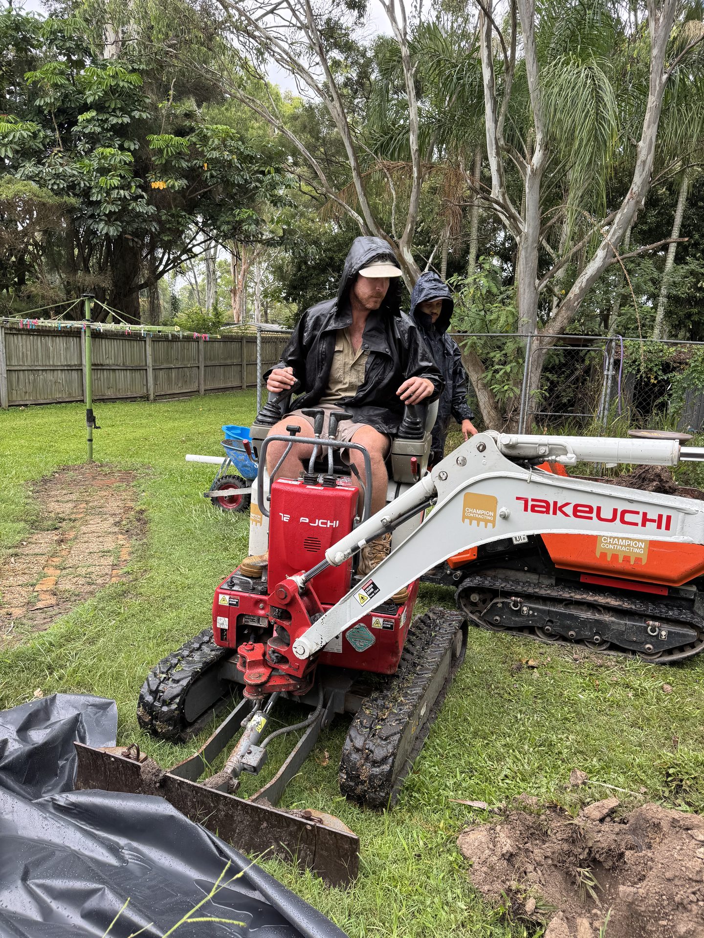 Mini Dig Solutions operator working a compact Takeuchi excavator in a tight backyard