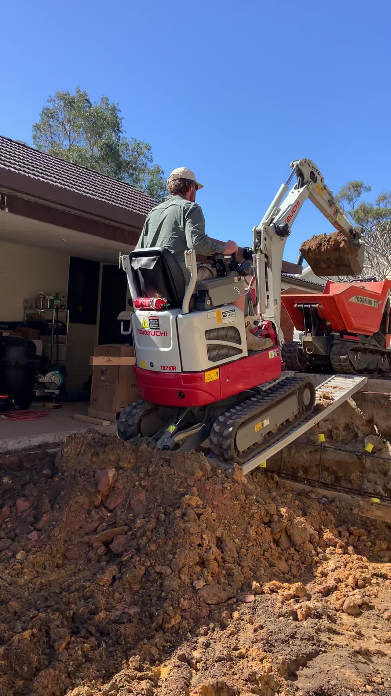 Compact excavator digging under a house in confined space
